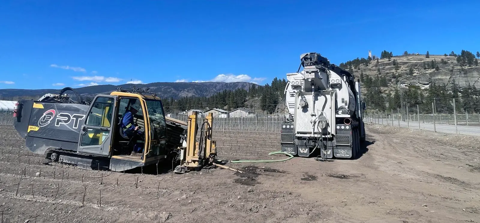 Vermeer horizontal directional drilling HDD rig executing trenchless utility pipeline installation in the rocky terrain of the BC Okanagan Interior.