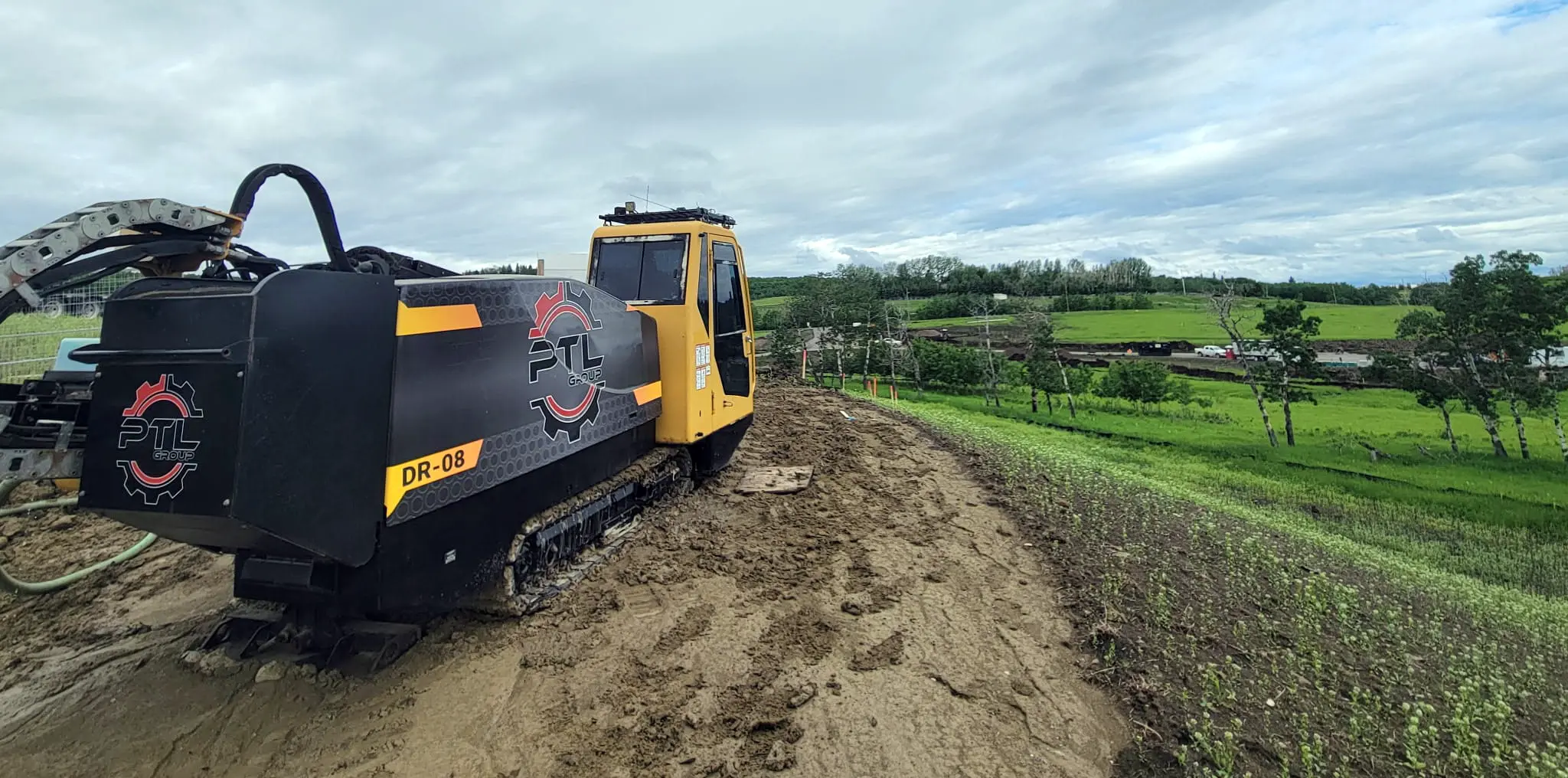 Tracked horizontal directional drill (HDD) rig positioned on a dirt path actively installing an underground trenchless utility pipeline on a civil construction site.